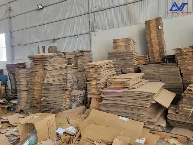 Giấy carton phế liệu được gấp phẳng và xếp gọn tại kho trước khi thu gom